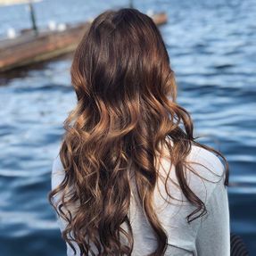 Kvinne med brunt krøllete hår foran sjø